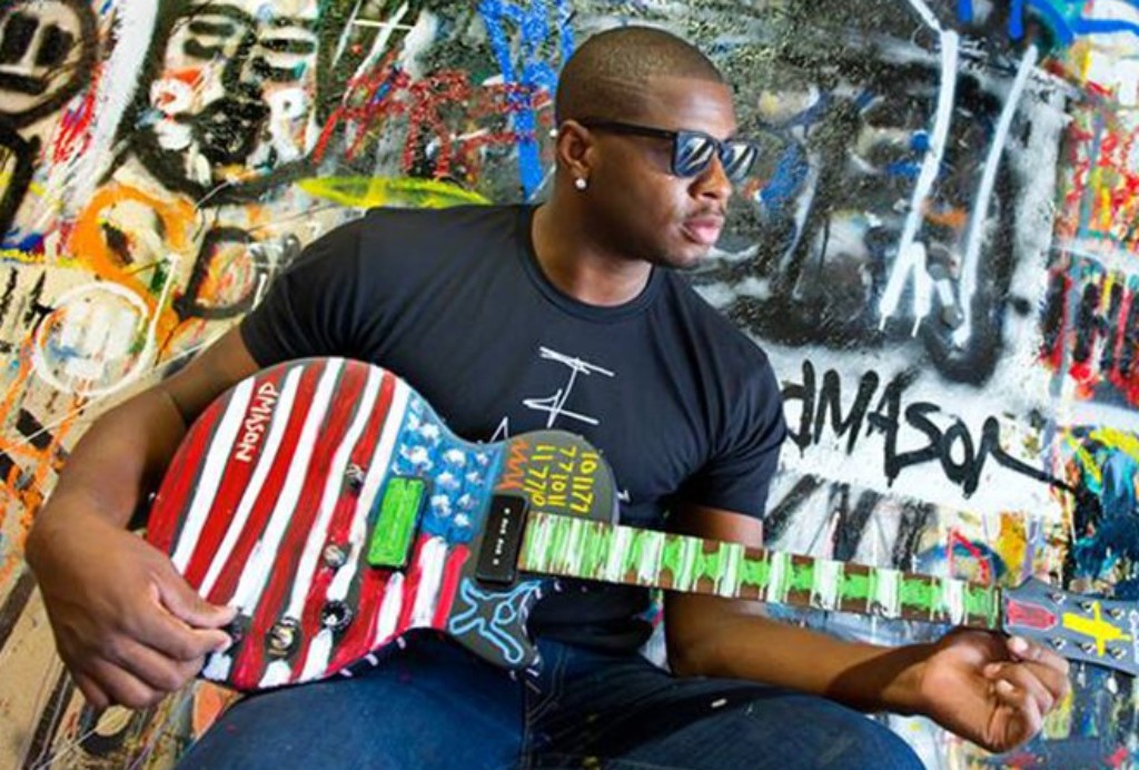 Man wearing shades playing a guitar