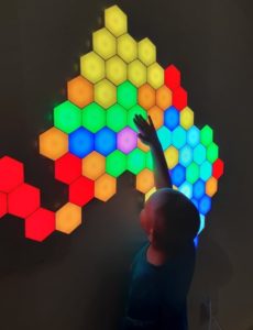 A young child explores an interactive display with colorful panels at an indoor exhibition.