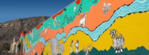  brightly painted mural featuring a river, railroad tracks and natural imagery.
