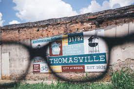 A mural of the creative district of Thomasville, Georgia, on a wall located in a vacant lot as seen through one eyeglass lens